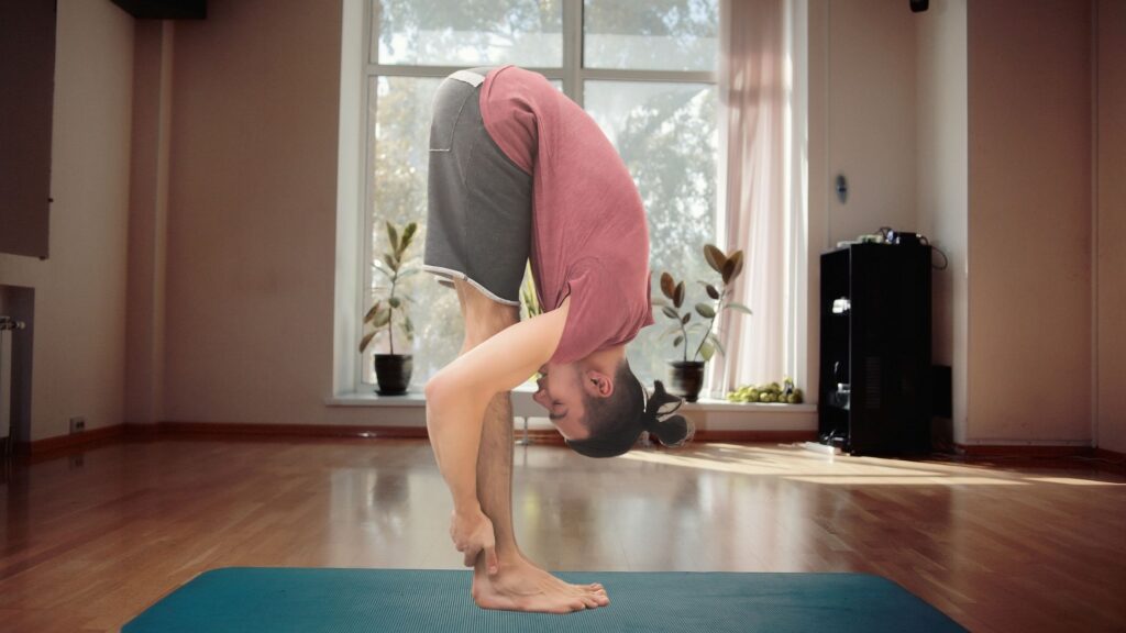 Man doing the Forward Bend on a blue mat indoors