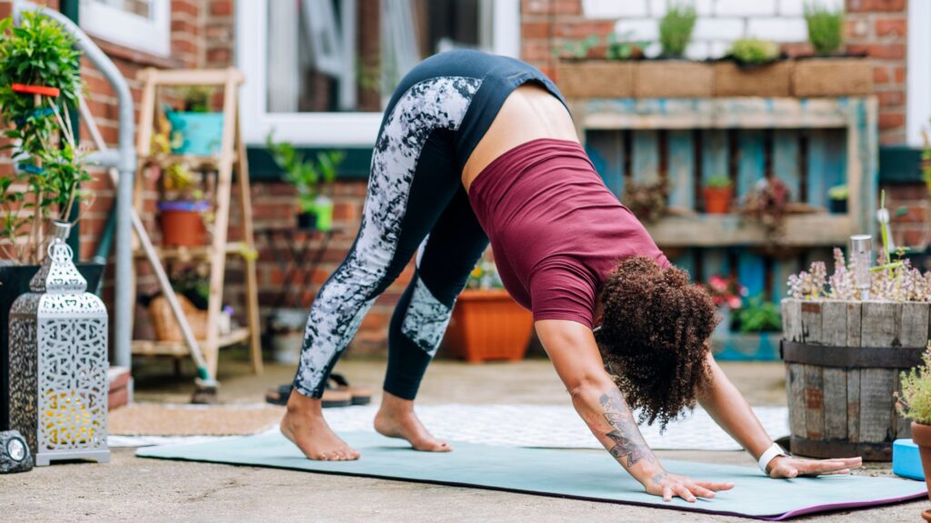 Woman doing the Downward dog, on a yoga mat outdoors